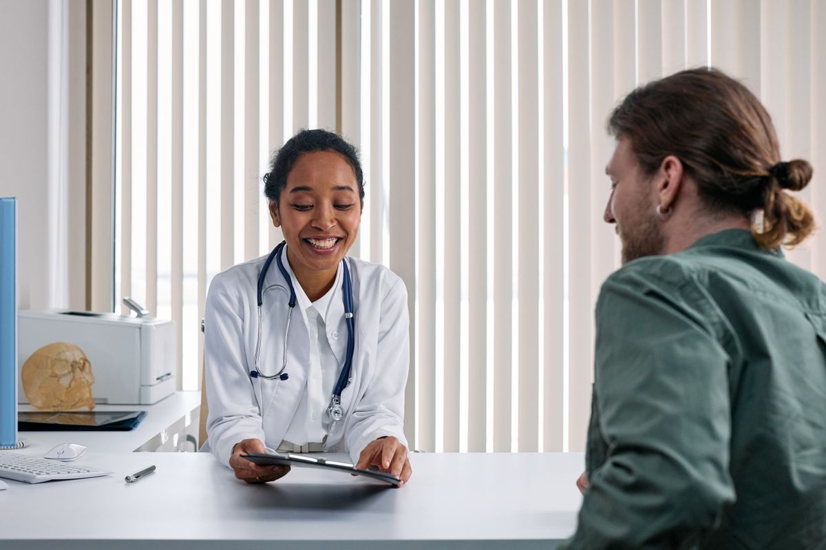 A doctor and patient in an easy, unhurried conversation in a bright consulting room
